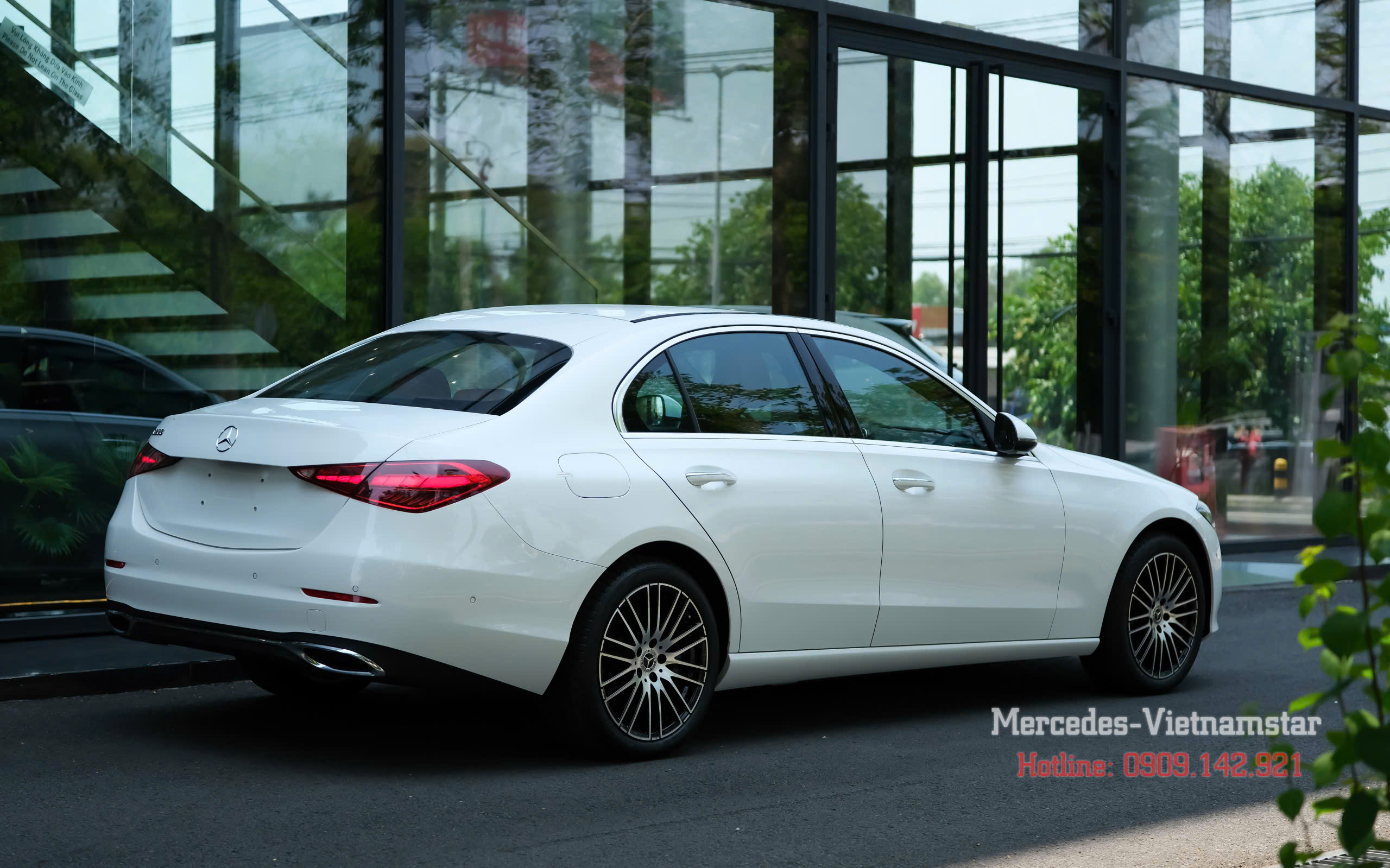 Xe C200 Avantgarde Plus màu trắng đỗ trước showroom Mercedes-Benz hiện đại.